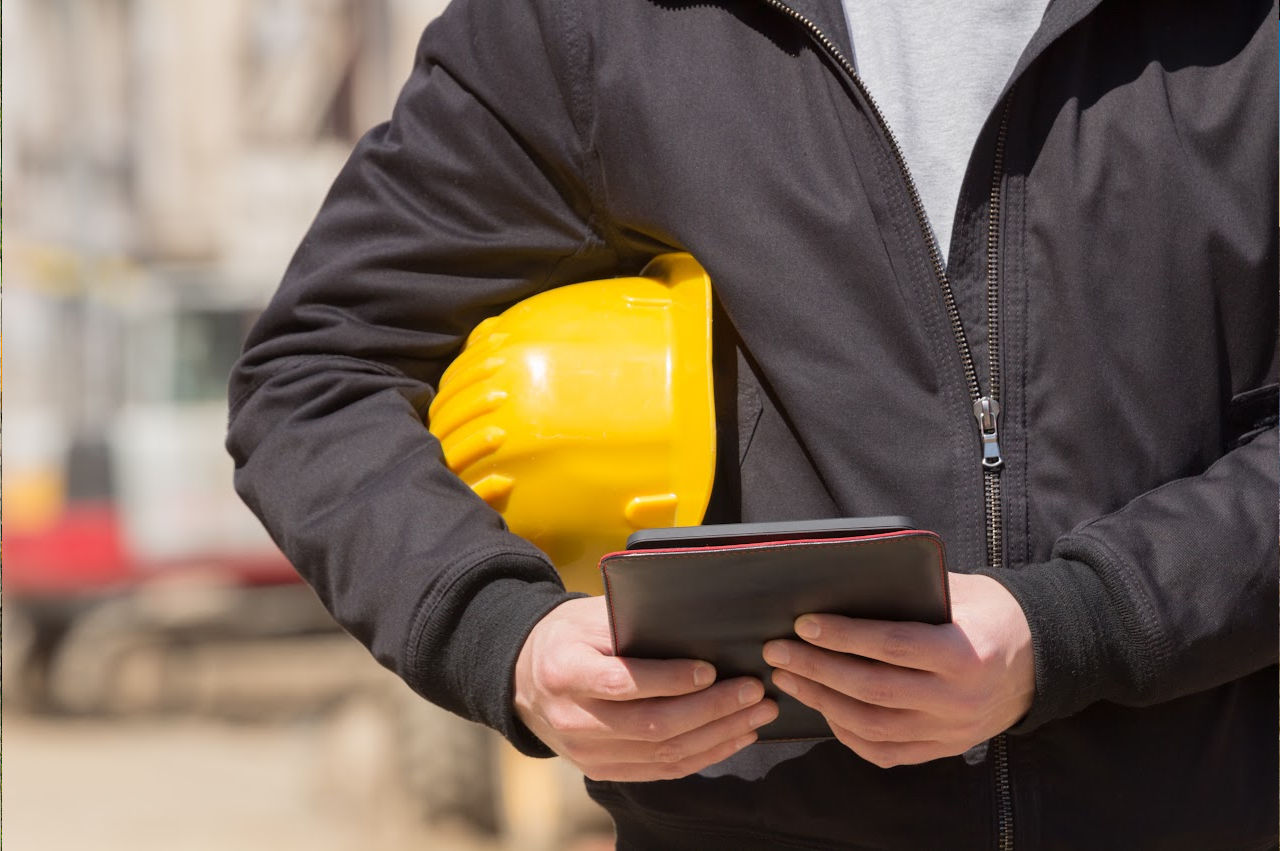 image of a person holding a hard hat and a tablet