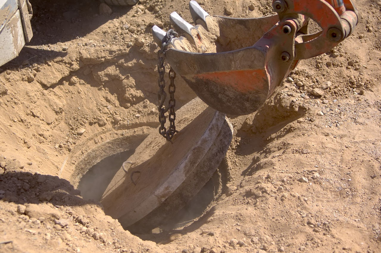 image of an excavator removing the lid to a septic tank 