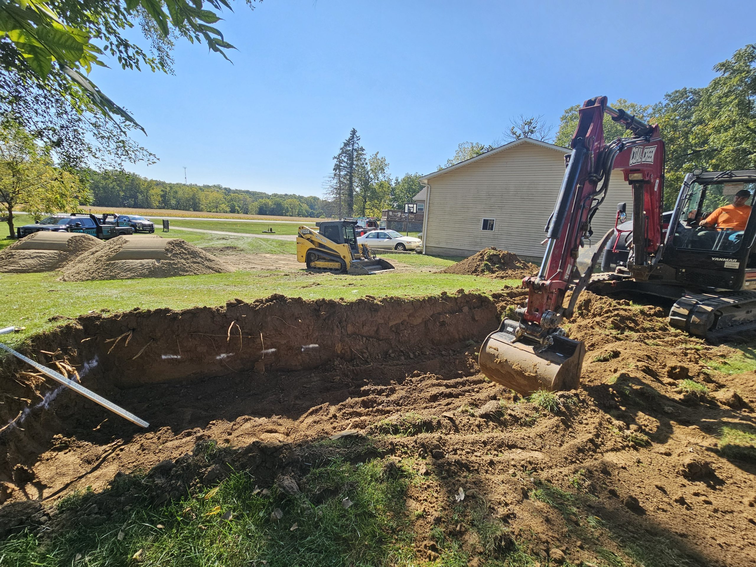 Colgan, Toulon(1) Excavator digs a trench in a grassy yard