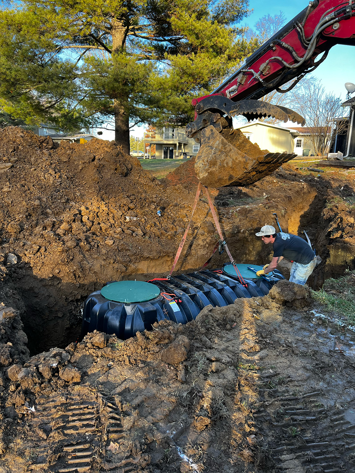 tank_instalation Excavator lowers a septic tank into a trench