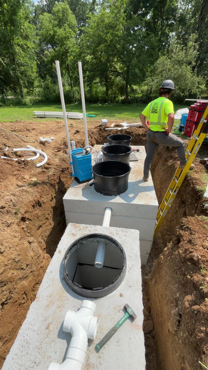 Excavator digs a trench in a grassy yard